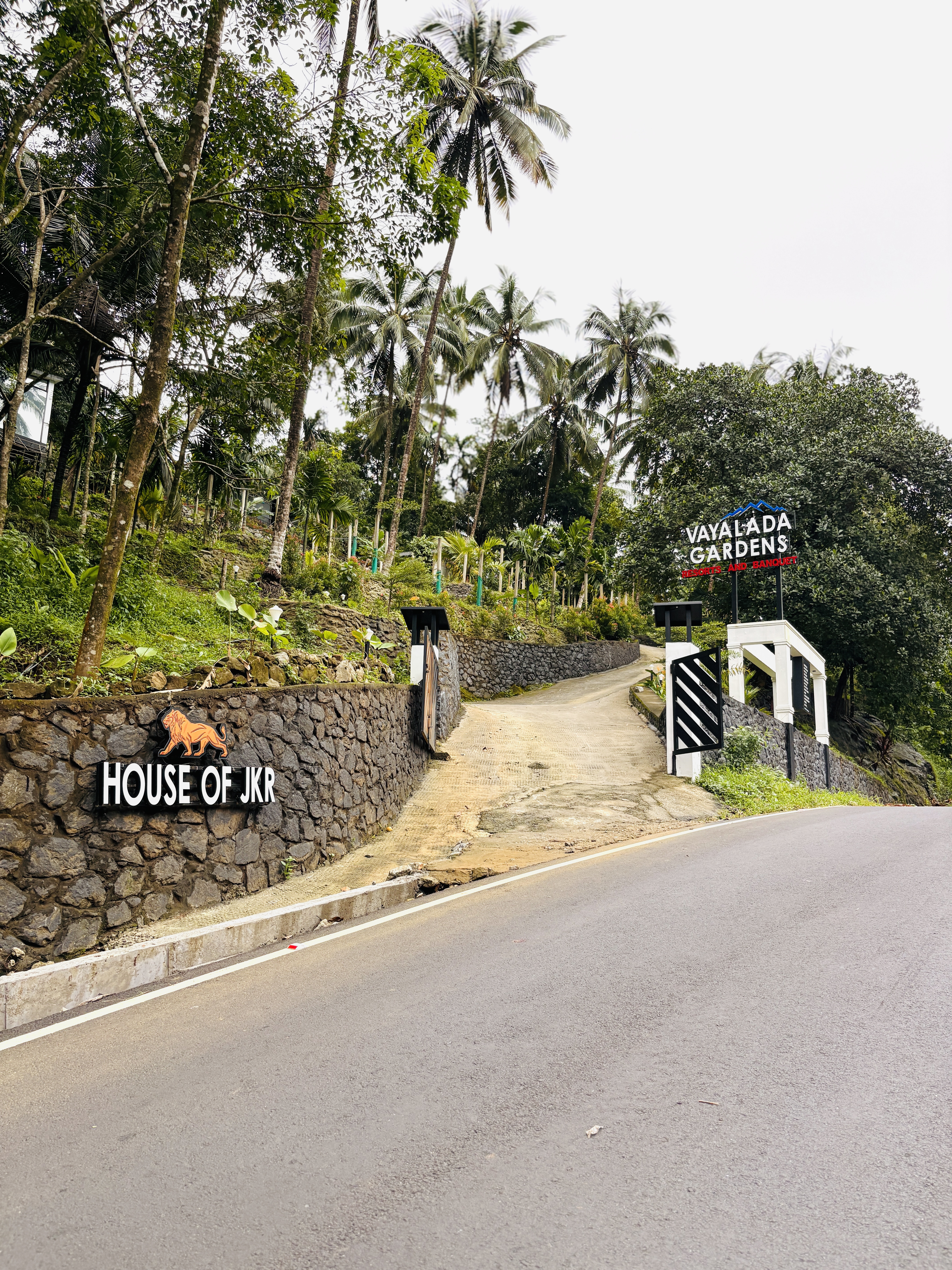 Spacious hotel room featuring a large bed with crisp white linens, green accent runner and pillow, two rolled towels placed on the bed, warm ambient lighting, wooden furniture, and a modern bathroom visible through a glass door. The setting conveys comfort and tranquility. No visible text in the image.