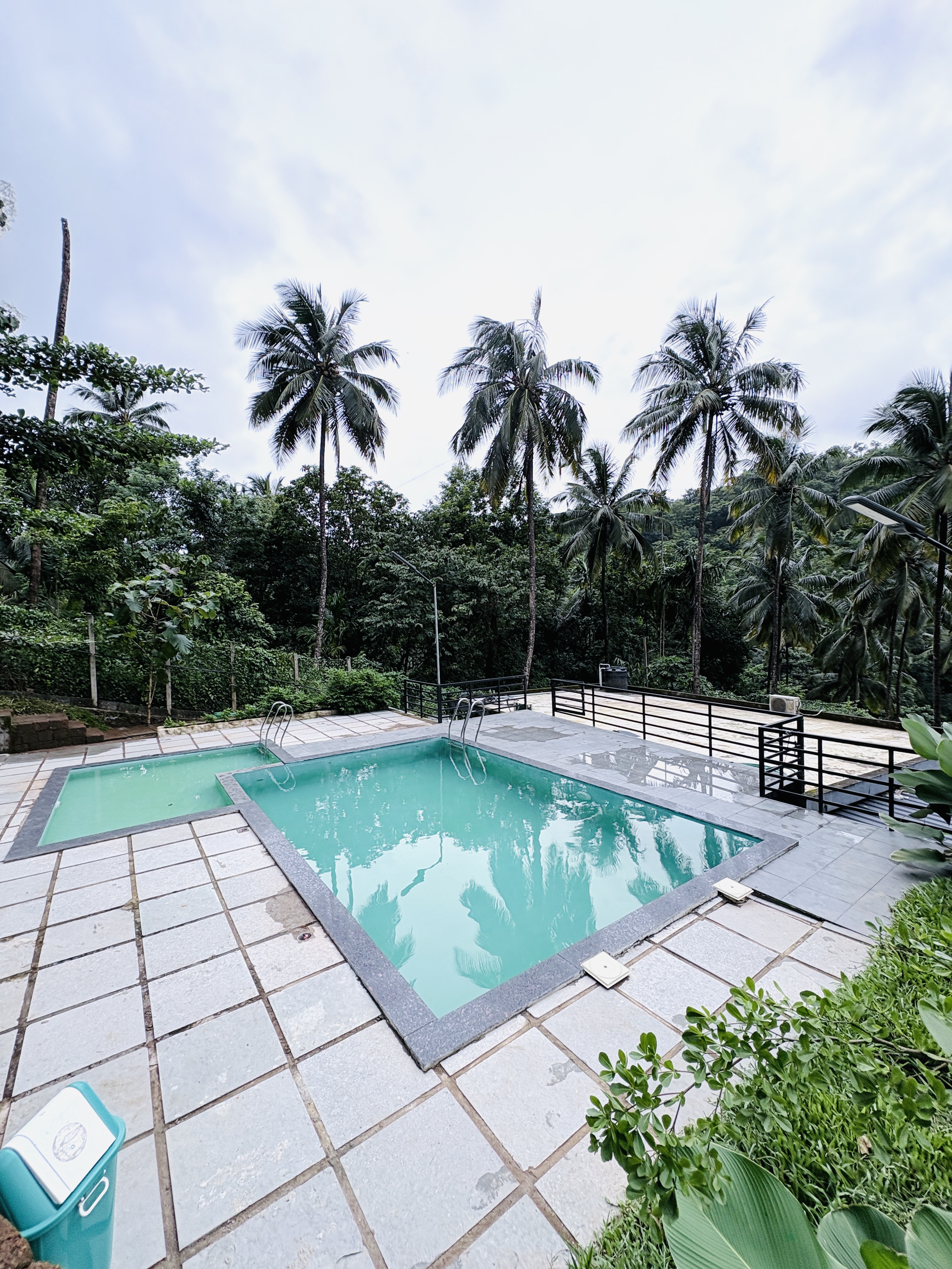 Modern lounge area with curved blue and orange seating, bean bags, and a large projection screen displaying a video game menu. Pink accent lighting streams from tall windows, creating a vibrant, playful environment ideal for socializing or gaming. No visible text. The mood is energetic and inviting.