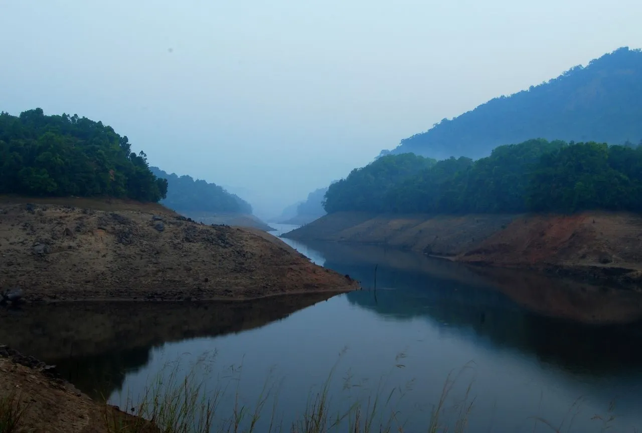 Kakkayam Dam near JKR Gardens Resort: scenic reservoir surrounded by lush green hills, ideal for nature walks, picnics, boating, and wildlife spotting. No visible text.