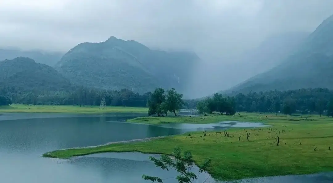 Kariyathumpara near JKR Gardens Resort: peaceful riverside getaway with lush greenery, rolling hills, and tranquil water, ideal for picnics, nature walks, and family outings. No visible text.