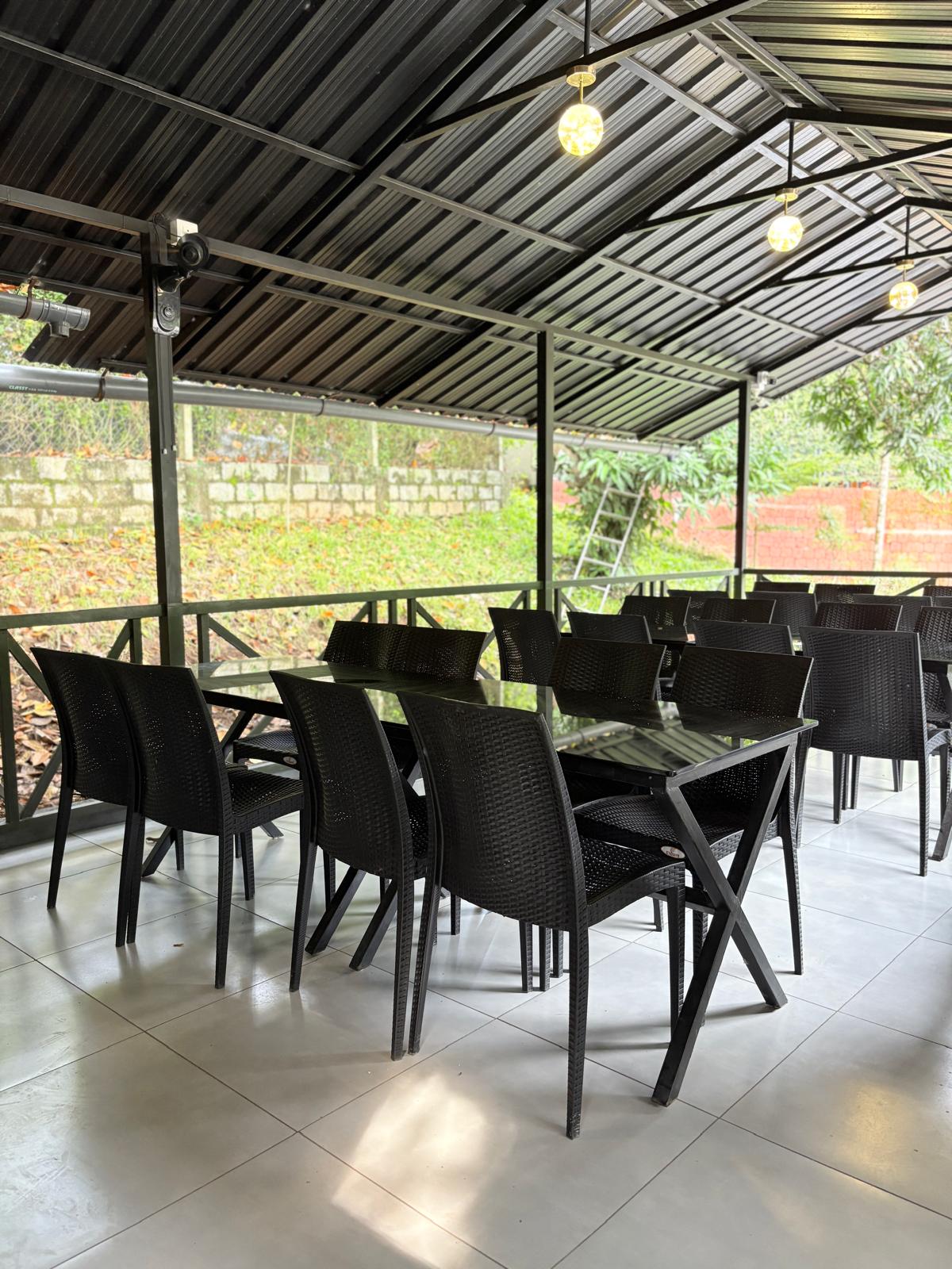 Buffet spread at JKR Gardens restaurant featuring a variety of Indian and continental dishes in stainless steel chafing dishes, neatly arranged on a long counter with decorative plants and warm lighting. The setting is lively and welcoming, with guests serving themselves and enjoying the vibrant dining atmosphere. No visible text in the image.
